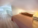 king bed in loft with ample lighting and flat screen tv
